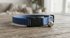 Close-up of a breakaway cat collar featuring a shiny metal bell attached to the strap, designed to alert British garden birds.