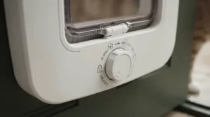 Close-up of a four-way rotary dial on a lockable cat flap showing in, out, locked, and unlocked settings.